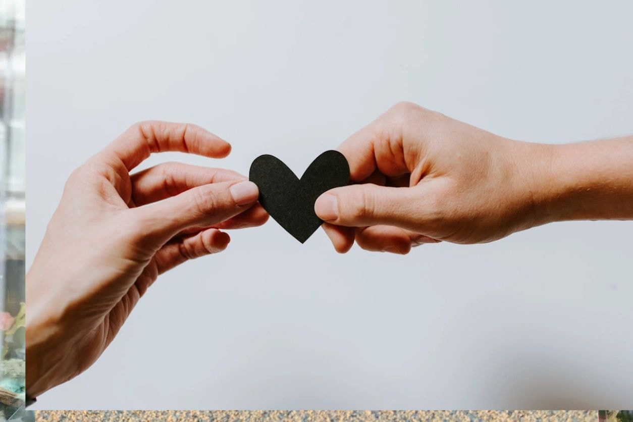 Two hands exchanging a heart — compassion and connection